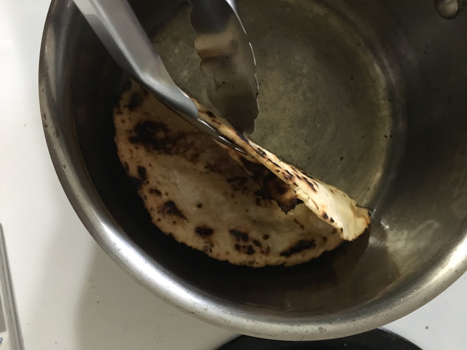I use the corner of the pot to hold the tortilla in shape.
